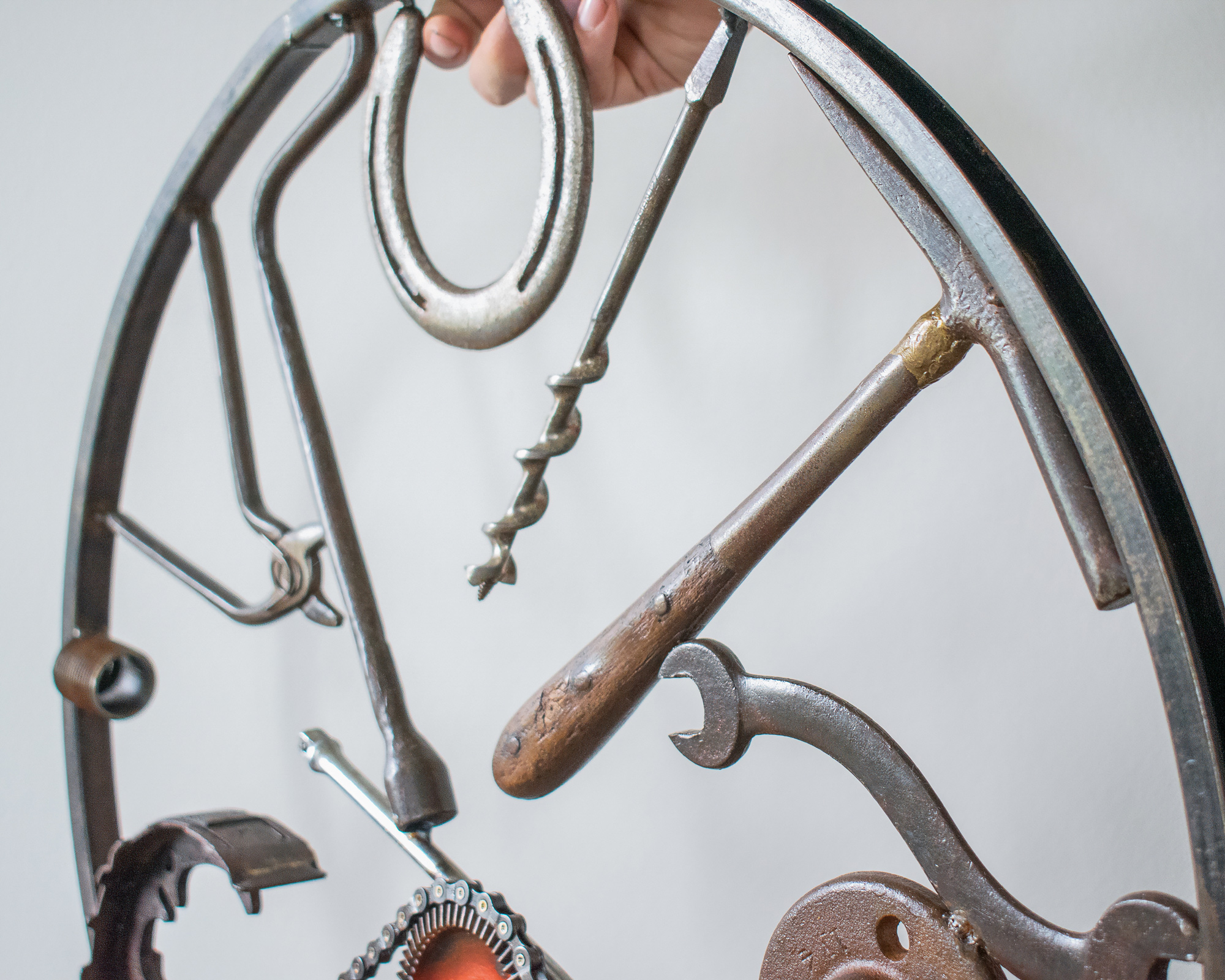 Close-up of horseshoe, drill bit, hammer, and wrench details in a music-inspired wall art sculpture.