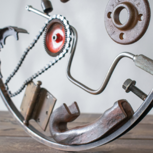 Close-up of reclaimed metal parts, chain, hinge, crank, and steel frame in a welded metal wall art collage.