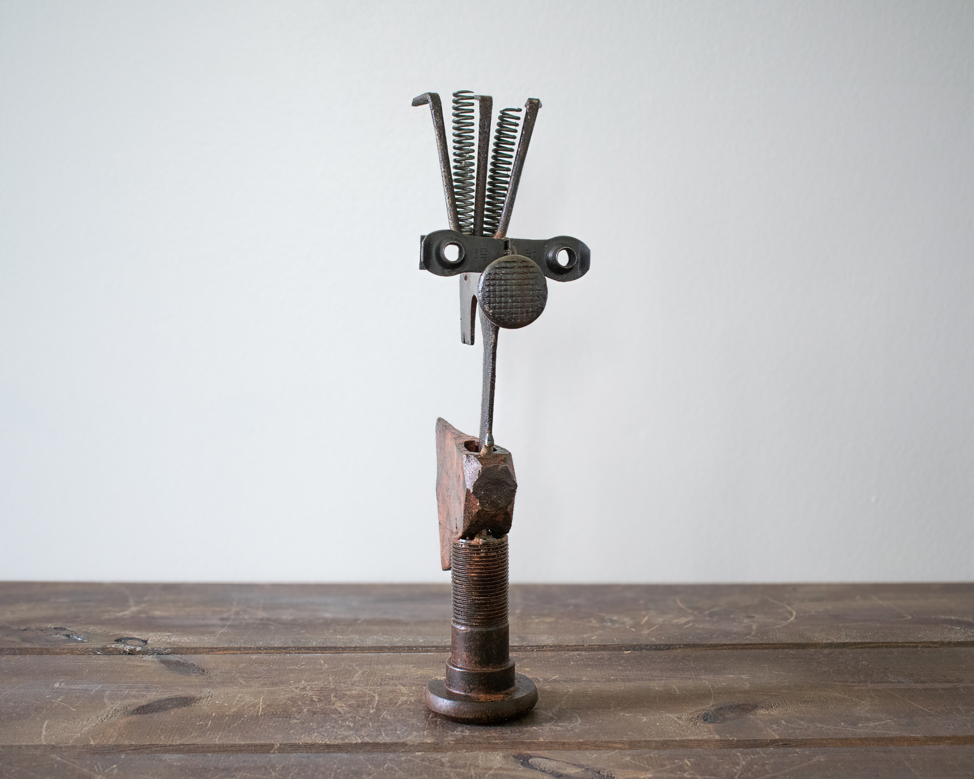 Welded metal hatchet sculpture made from reclaimed steel, old tools, springs, and a large bolt base.