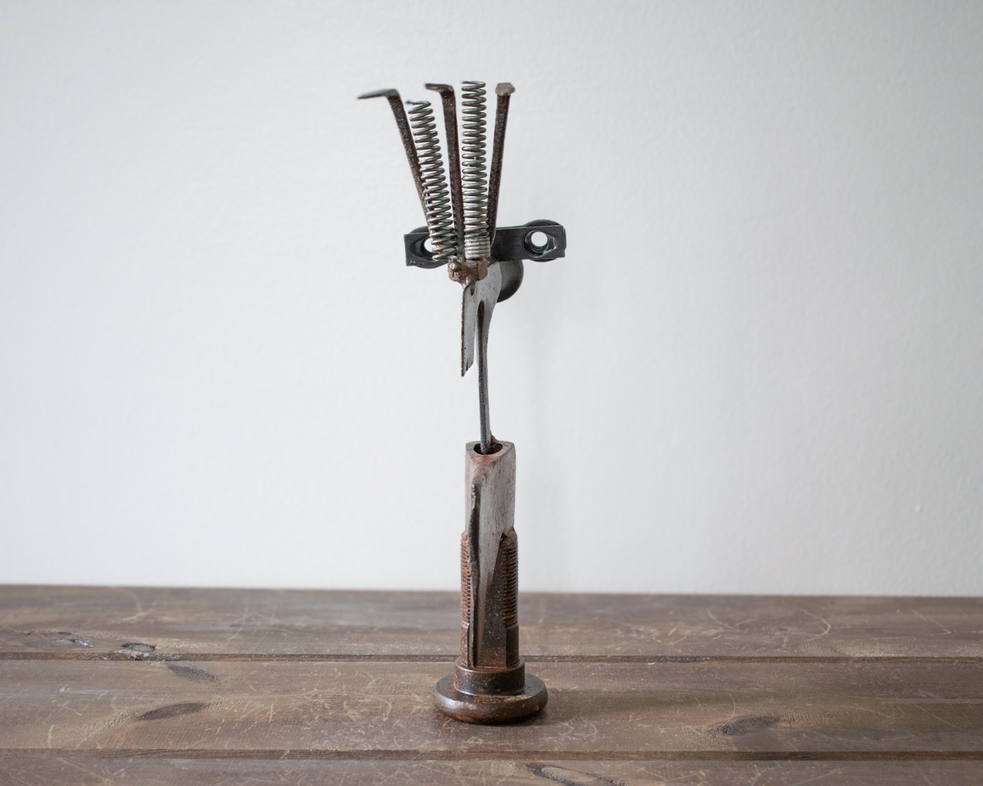 Back view of a welded scrap metal art sculpture showing the bolt base, steel body, and spring details.