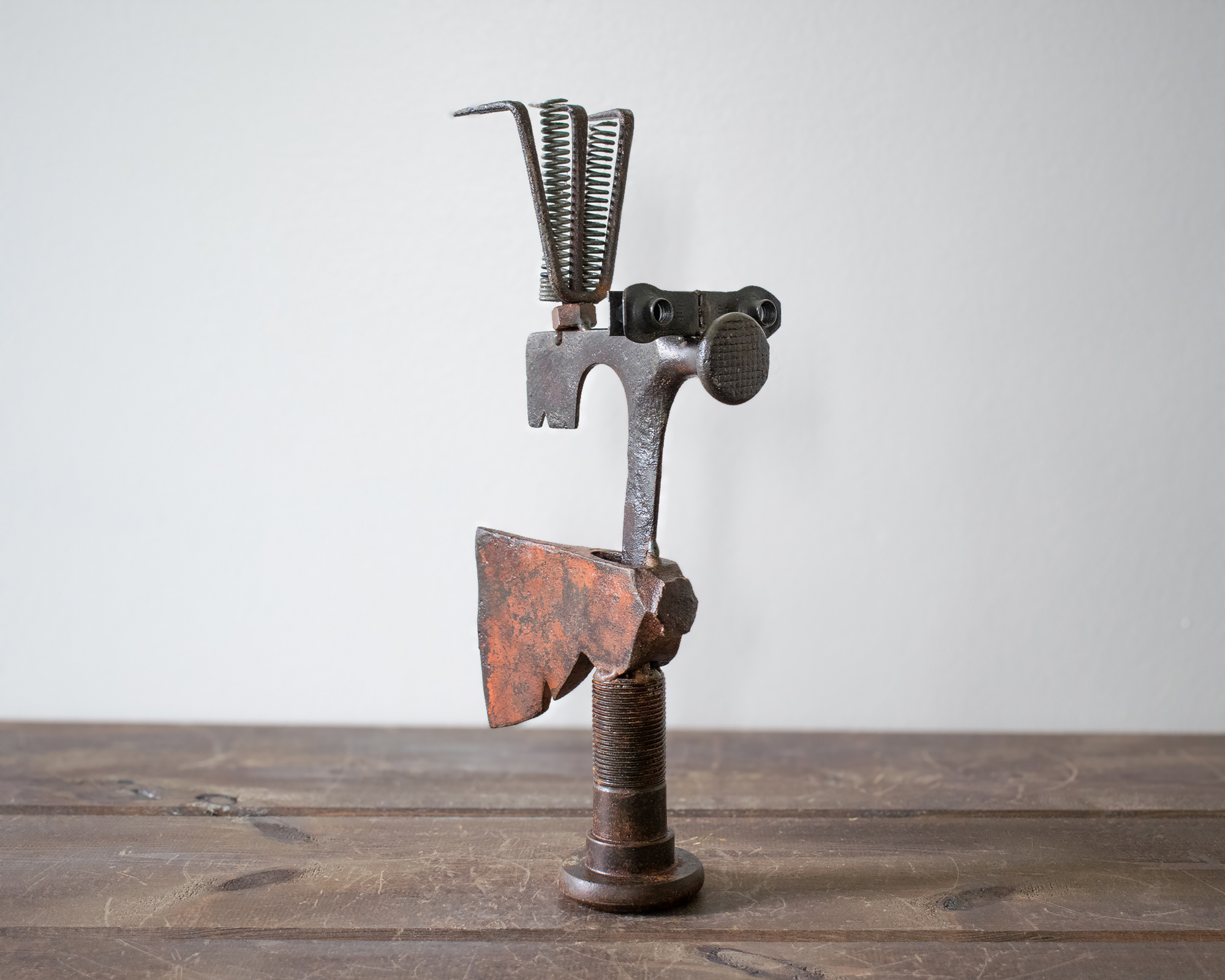 Angled view of Mr. Hatchet reclaimed metal art with axe head, springs, and textured raw steel finish.