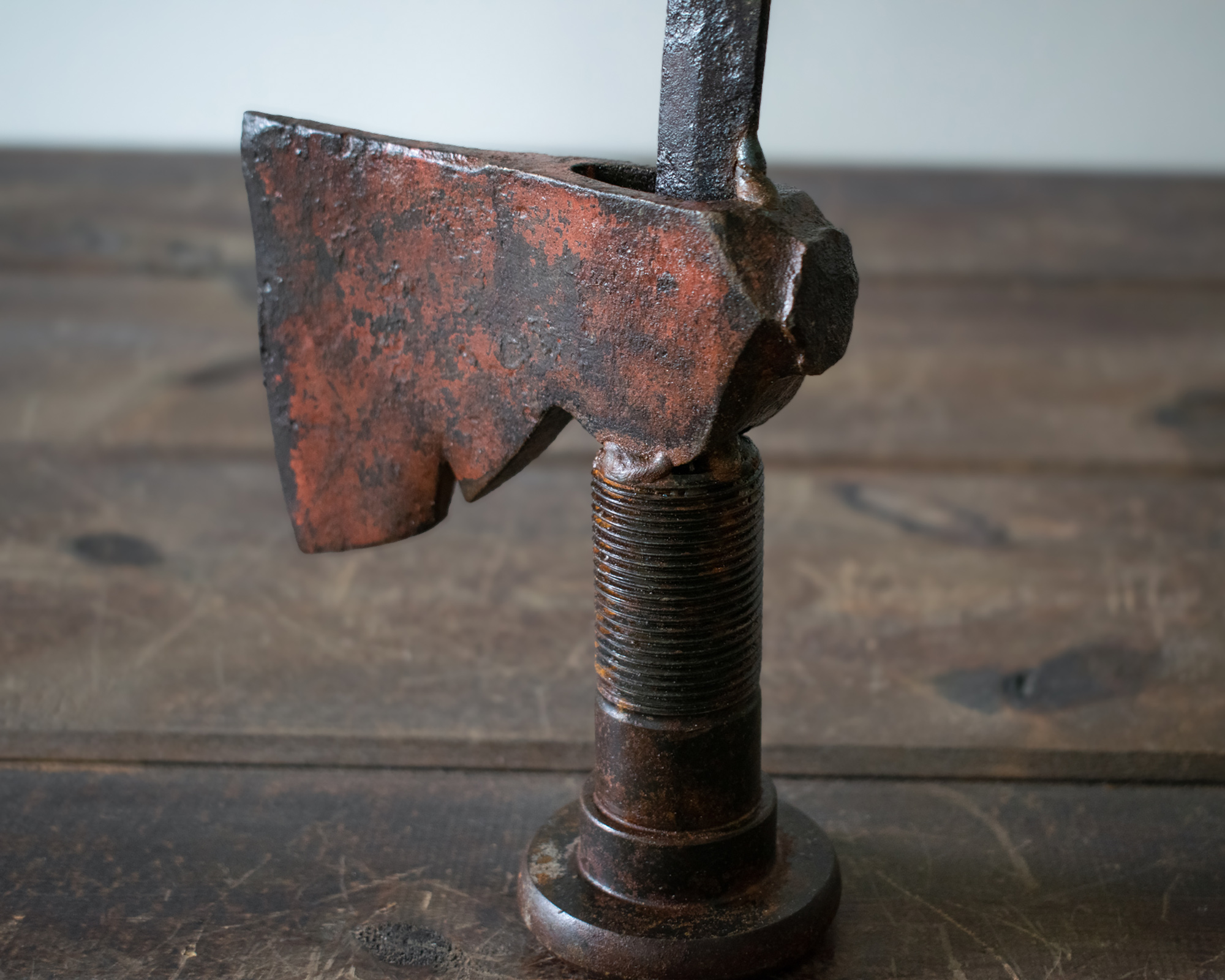 Close-up of the axe head and large bolt base on a welded metal hatchet sculpture made from reclaimed steel.