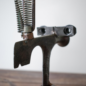 Close-up of the spring, rake, and axe head details on an industrial welded scrap metal art piece.