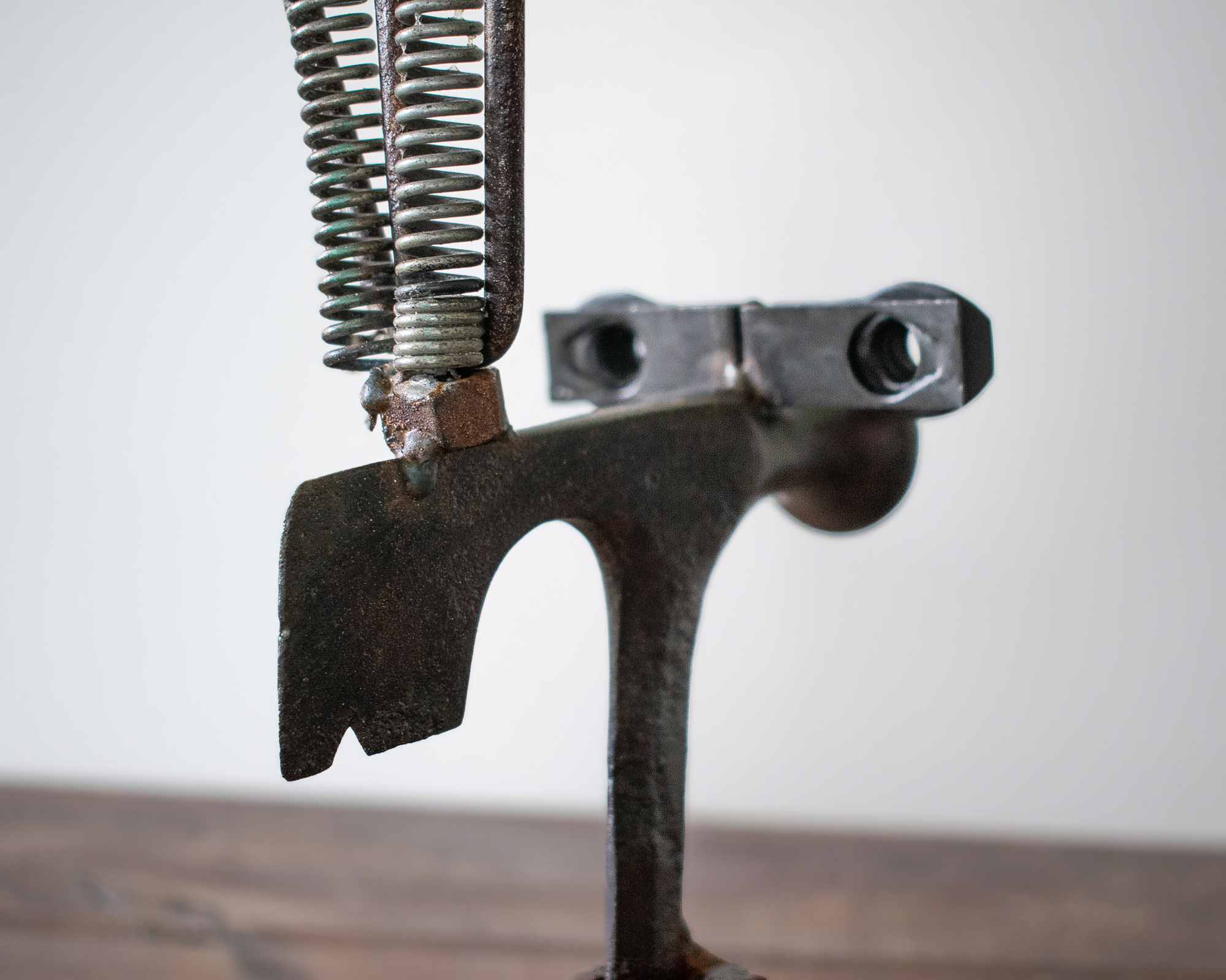 Close-up of the spring, rake, and axe head details on an industrial welded scrap metal art piece.