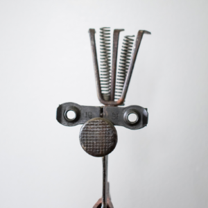 Close-up of welded metal hatchet sculpture's face detail made from old tool parts, springs, and reclaimed metal.