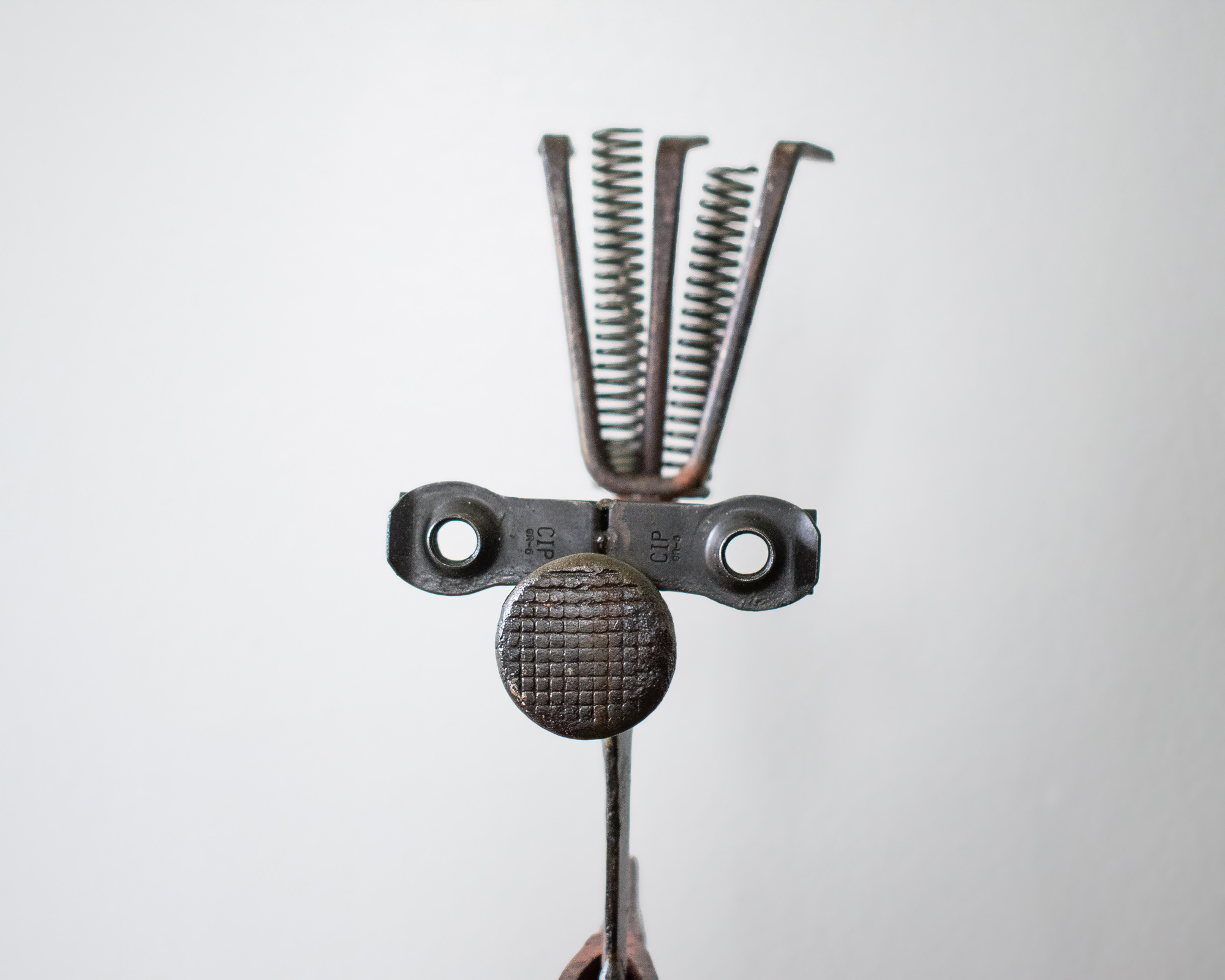 Close-up of welded metal hatchet sculpture's face detail made from old tool parts, springs, and reclaimed metal.